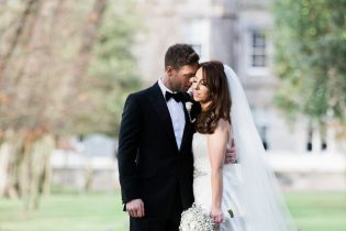 Bride in Suzanne Neville Gown and groom in black tie at a wedding at Carlowrie Castle in Edinburgh, Scotland