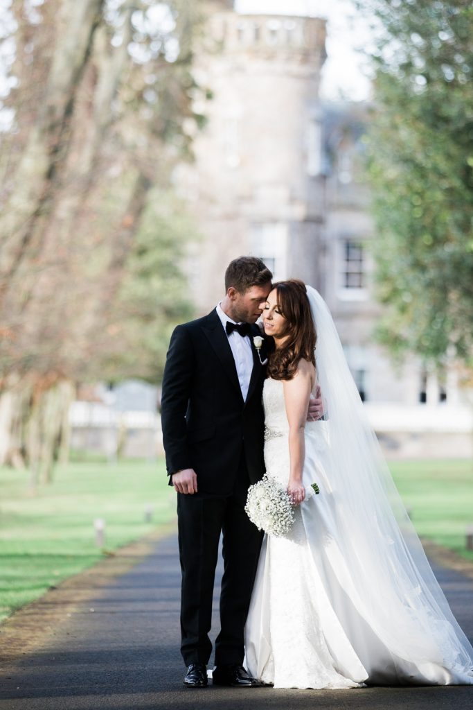 Bride in Suzanne Neville Gown and groom in black tie at a wedding at Carlowrie Castle in Edinburgh, Scotland