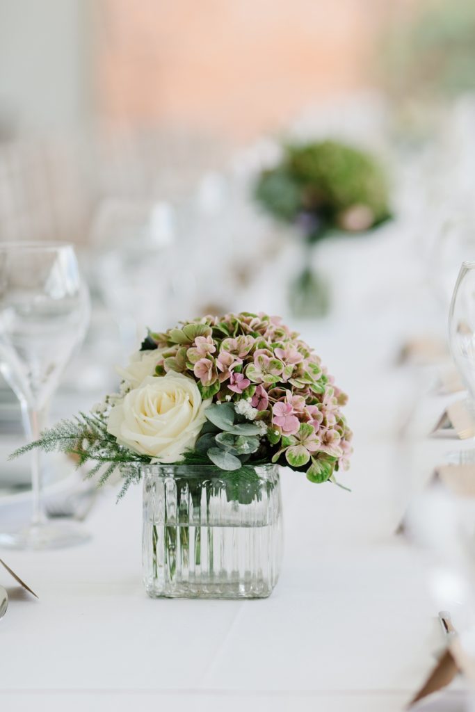 Table details by Cheshire wedding photographer at a Dorfold Hall wedding. Pretty rustic florals featuring roses and hydrangeas.