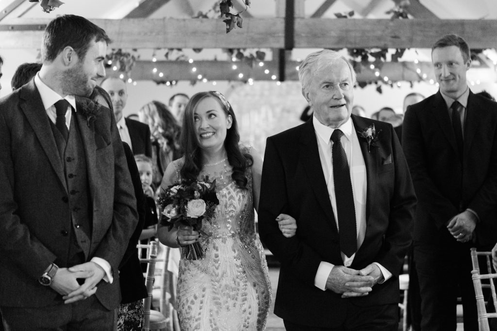 Black and white documentary wedding photography for a winter barn wedding ceremony .