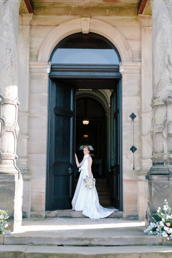 Bride at the door of Sandon Hall, wedding venue in Staffordshire for this bridal inspiration shoot featuring a Jesus Peiro wedding gown. Photography by Jade Osborne Fine art wedding photographer.