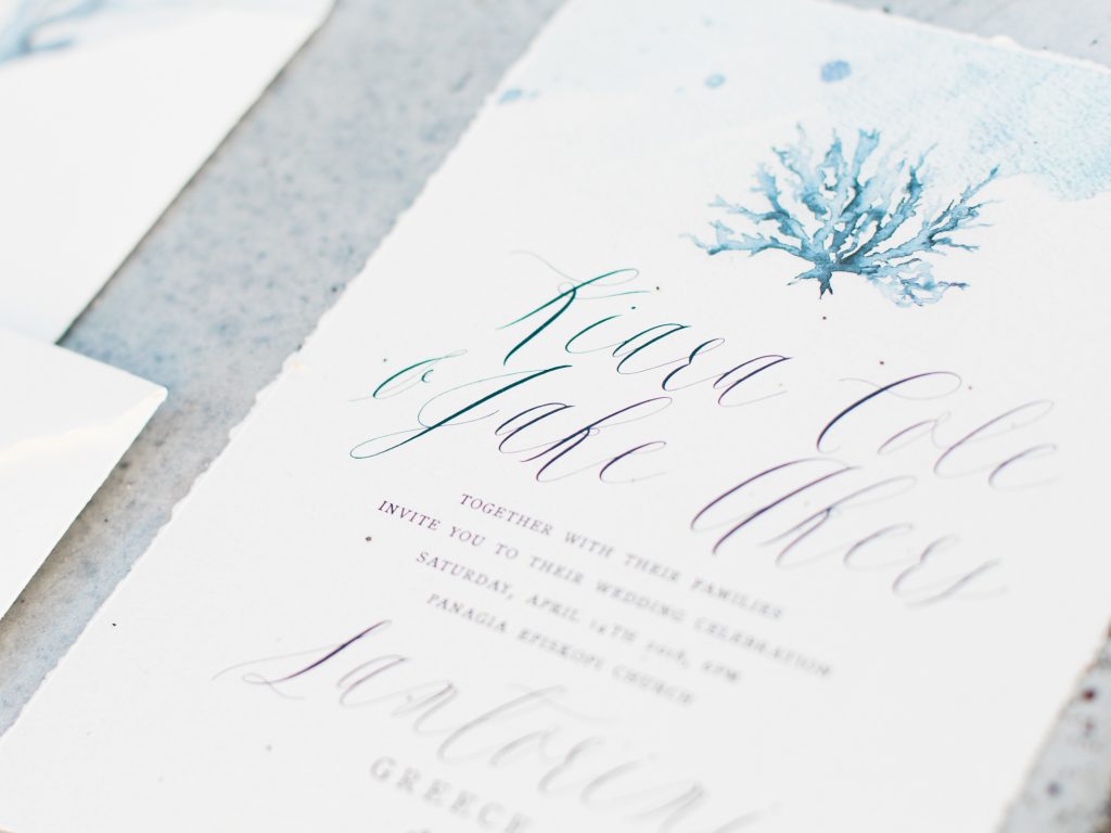 Stationery for a beach wedding in Santorini featuring white and blue calligraphy