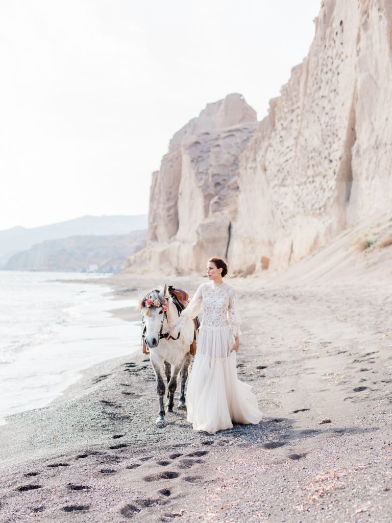Santorini beach wedding editorial featuring white horse with floral crown
