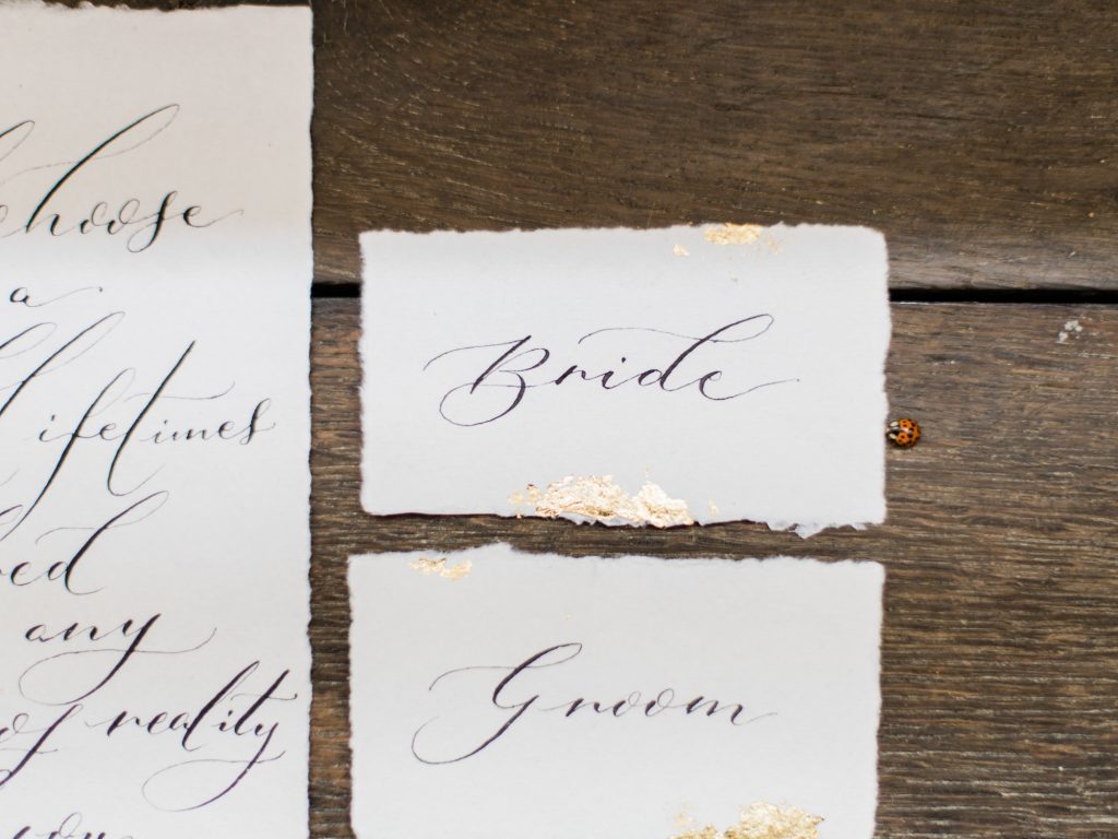 Wedding escort cards handmade paper with calligraphy and gold foil for a wedding inspiration shoot at a country house wedding venue in the UK.