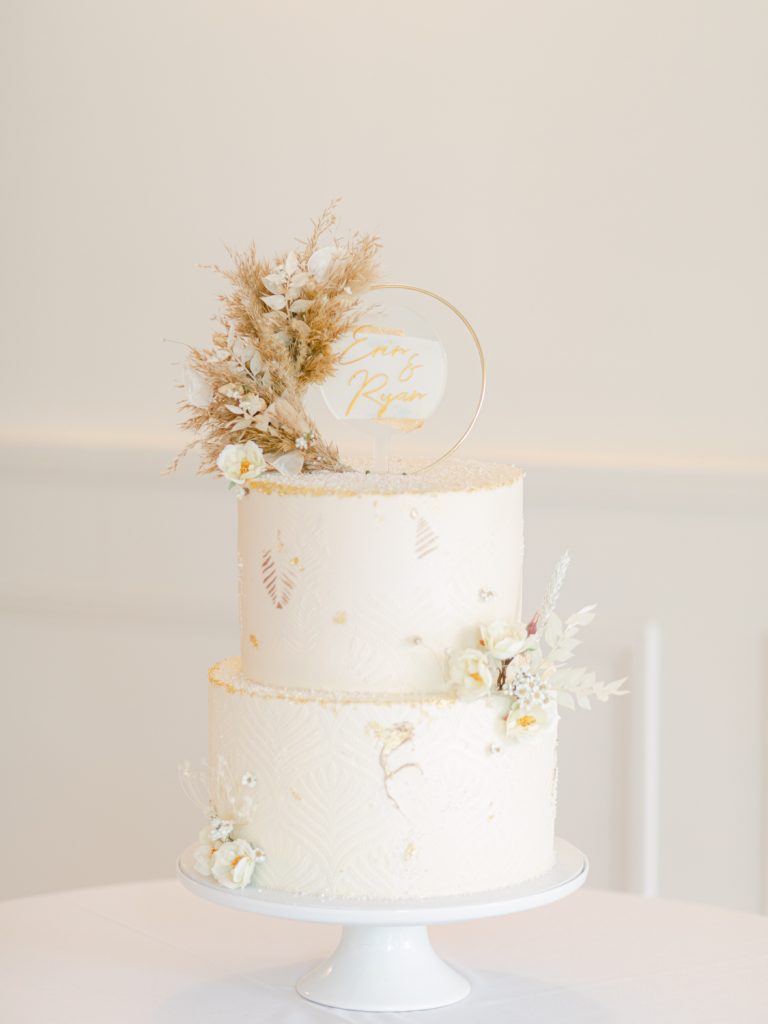 Pretty, neutral wedding cake design with cream icing and dried flowers as decoration.