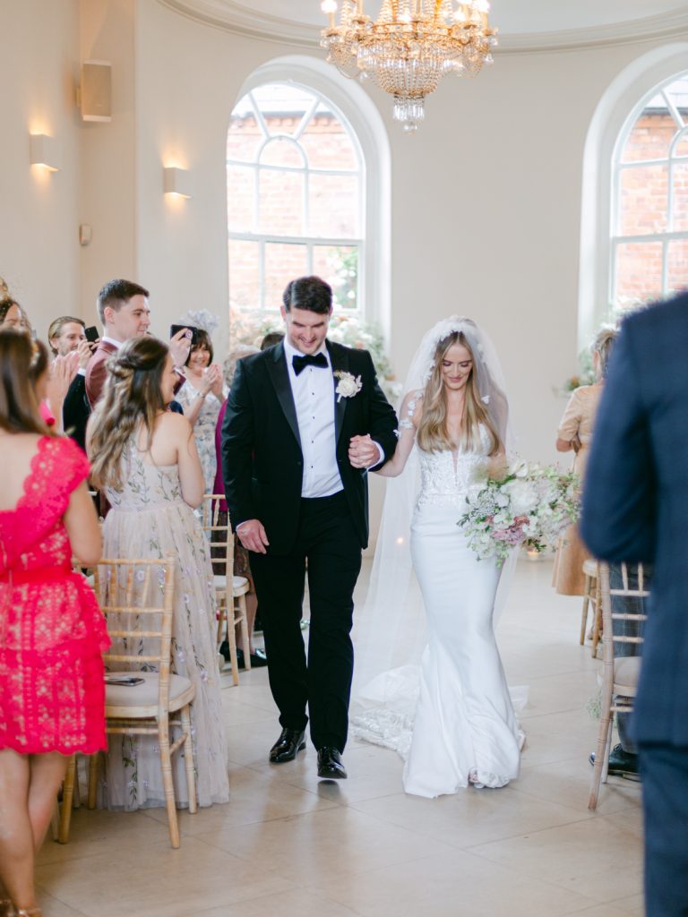 The couple walk back down the aisle hand in hand as newlyweds.