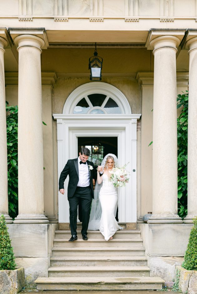 The couple walk outside the front of the venue, down the steps into the gardens.