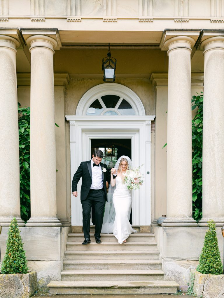 The couple walk outside the front of the venue, down the steps into the gardens.