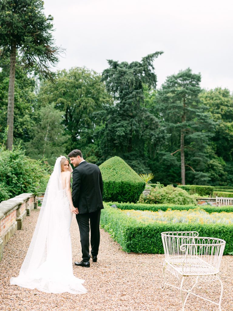 Full length shot of bride and groom holding hands in the gardens at Iscoyd Park.