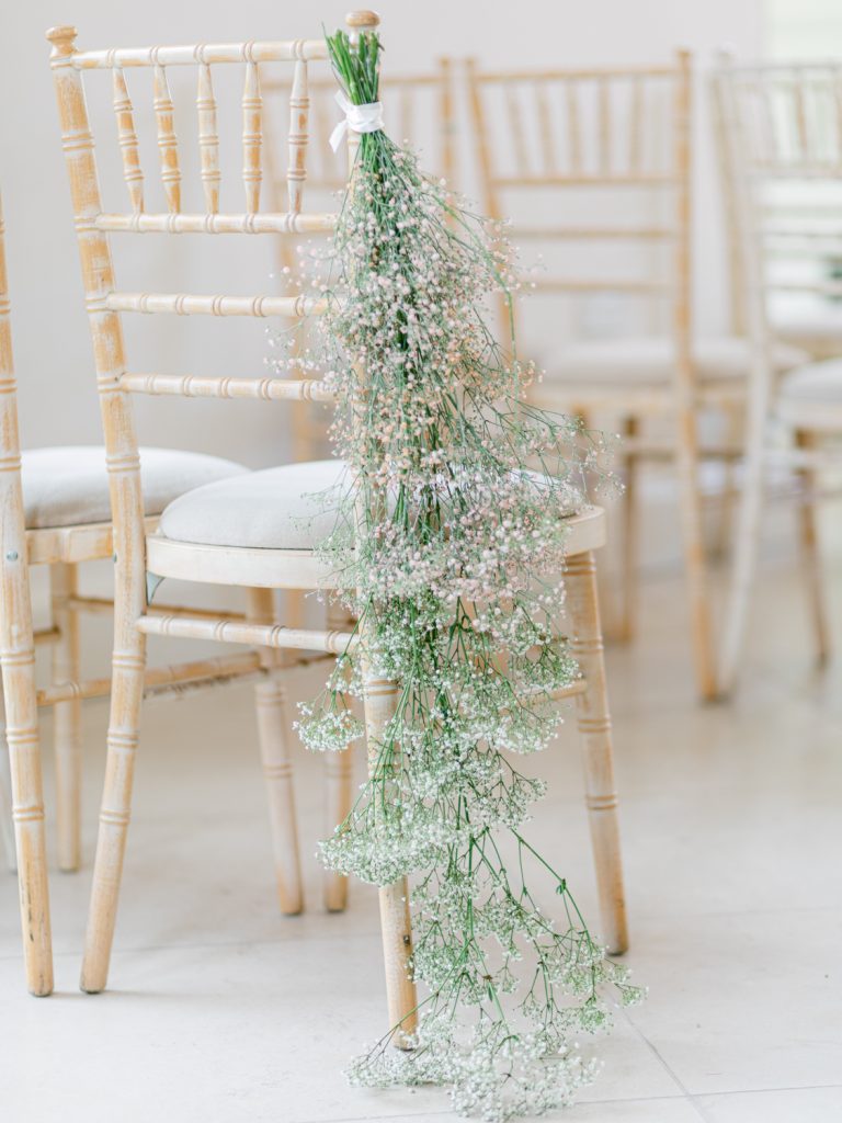 Simple floral chair sways in the ceremony room featuring gypsophila.