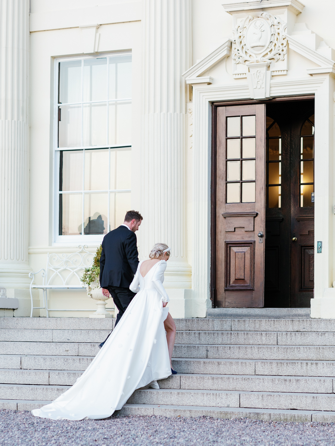 Jess and Lewis walking up the main steps of Hawkstone Hall towards their reception