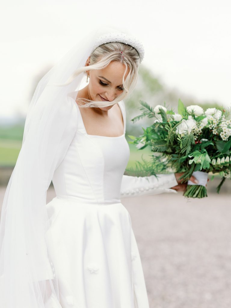Jess holding her bridal bouquet outside with the wind gently blowing her hair.
