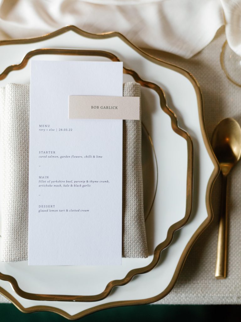 Luxury gold-trimmed crockery, gold cutlery and textured table linen for the wedding breakfast.